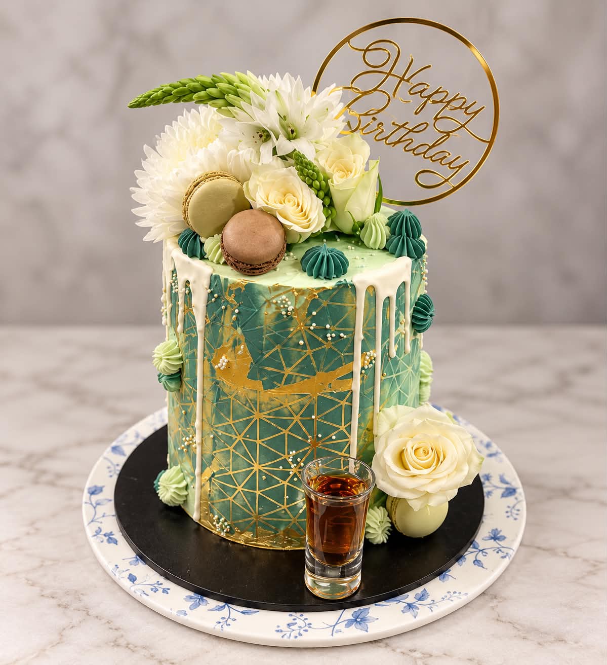 Green and gold custom birthday cake with flowers and macarons